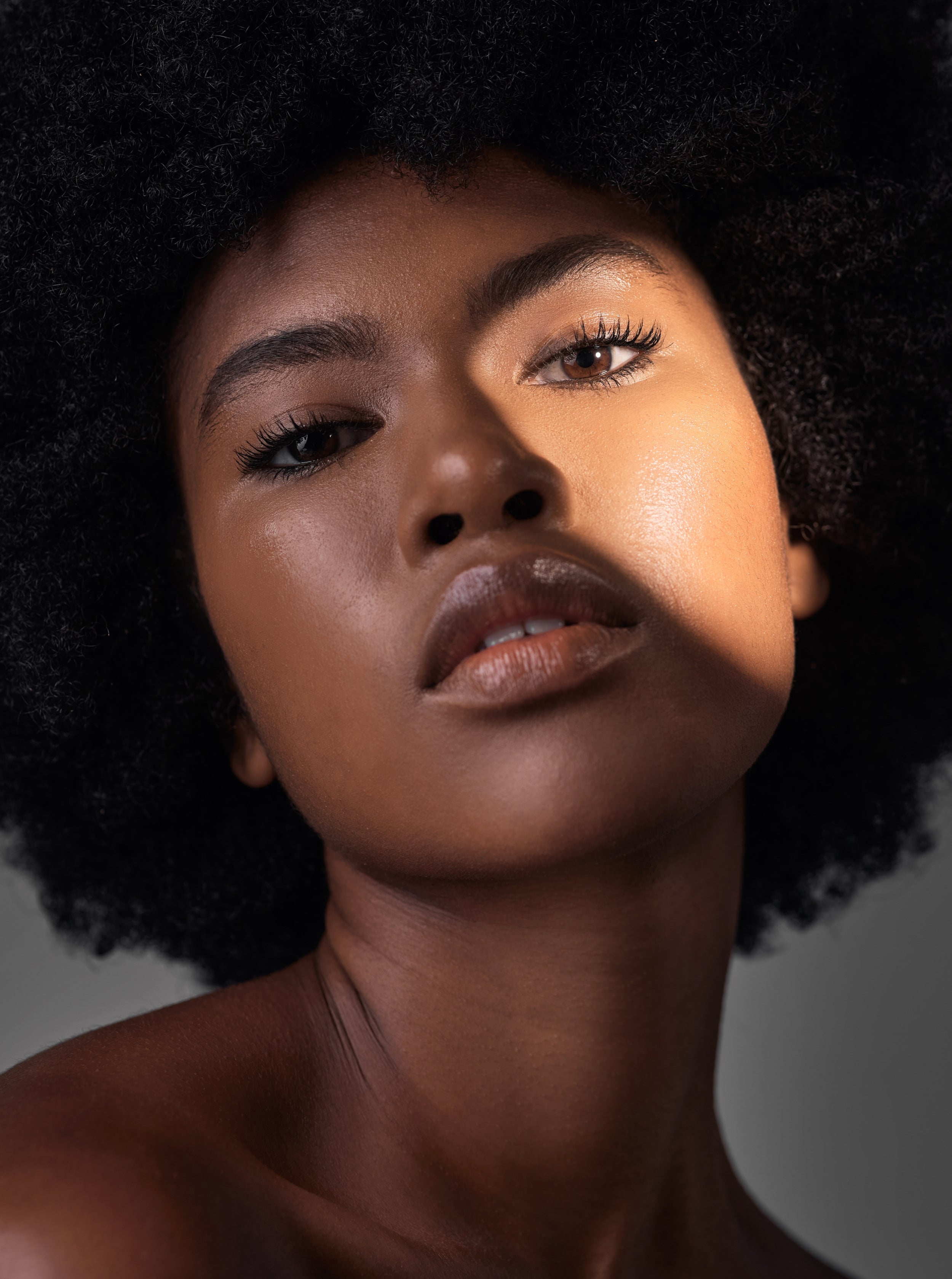 dark-portrait-light-makeup-black-woman-with-beauty-foundation-natural-facial-cosmetics-spa-skincare-shine-studio-lighting-face-shadow-african-person-with-glowing-skin-grey-background.jpg